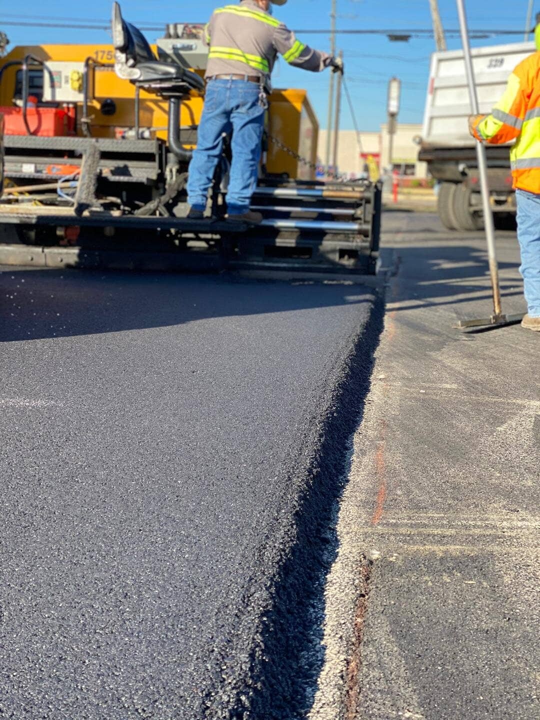 Close-up of paver machine and crew spreading asphalt