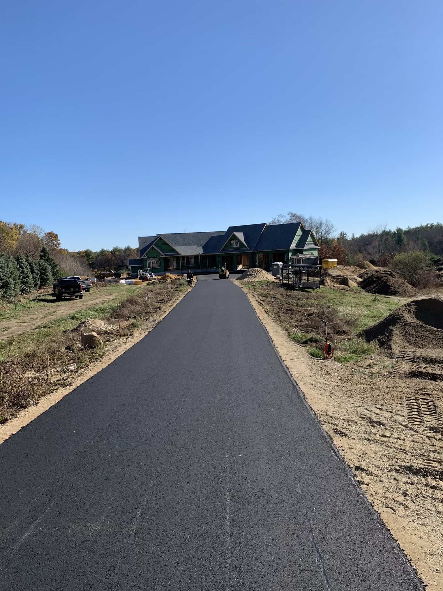 New asphalt driveway leading to a home under construction